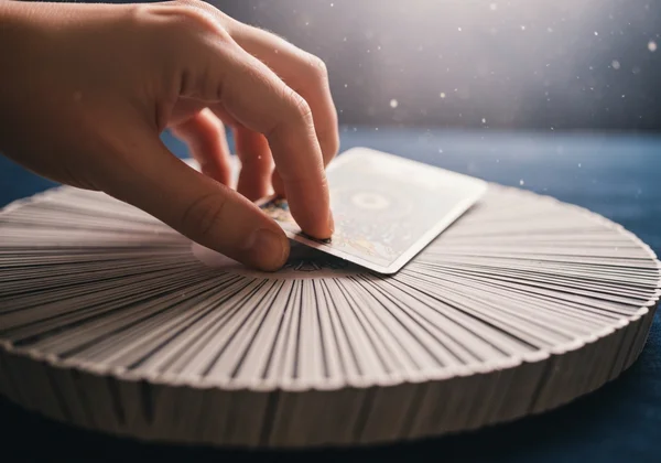 A hand pulling a single tarot card from a deck.
